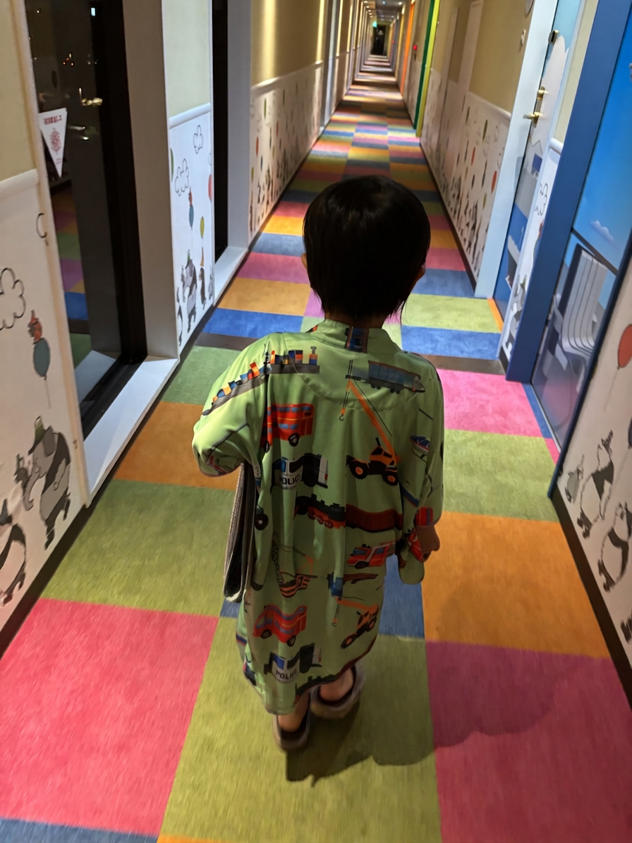 乗り物ルーム専用パジャマ カラフルなカーペットの廊下を歩く子供の背中