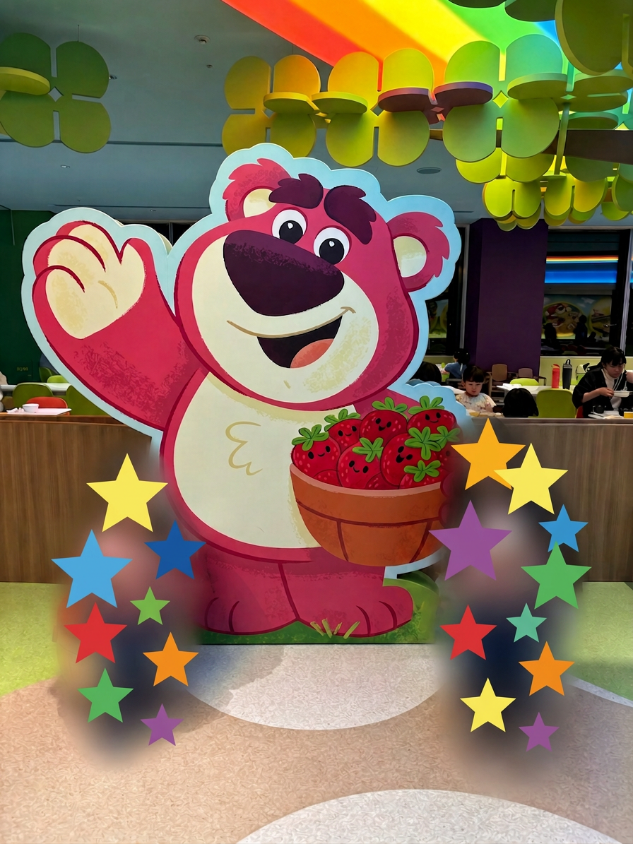 ロッツォガーデン カラフルな天井の下で、イチゴの入ったボウルを持ったピンク色の熊のキャラクターが描かれた大きな看板。周りには星型の装飾があり、子どもたちが楽しそうに過ごしている様子。