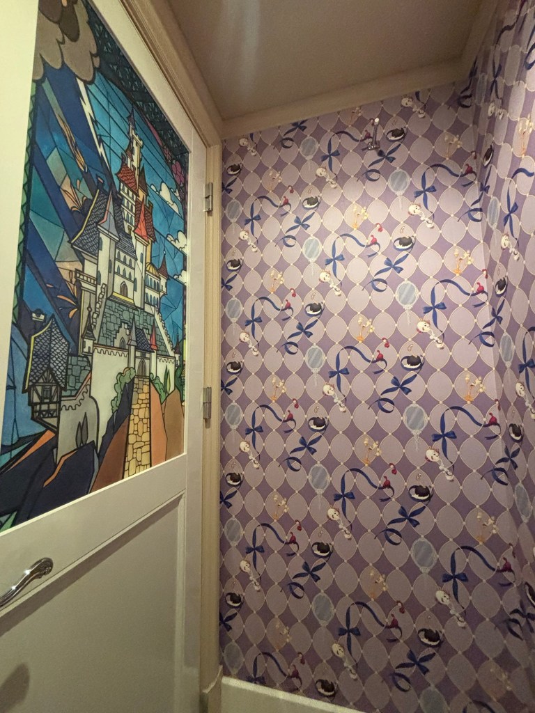 城のデザインが施されたドアと、紫色の壁紙があるトイレの内部