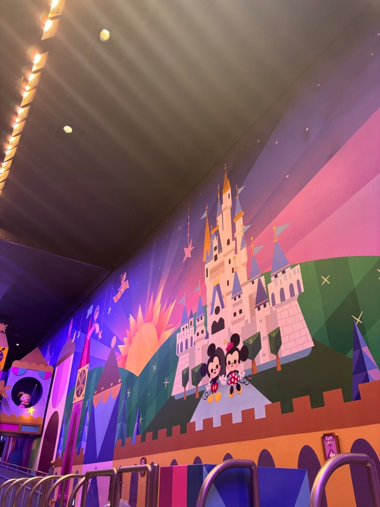 カラフルなディズニーの壁画、ミッキーマウスとミニーマウスが描かれた城と風景が背景にある
