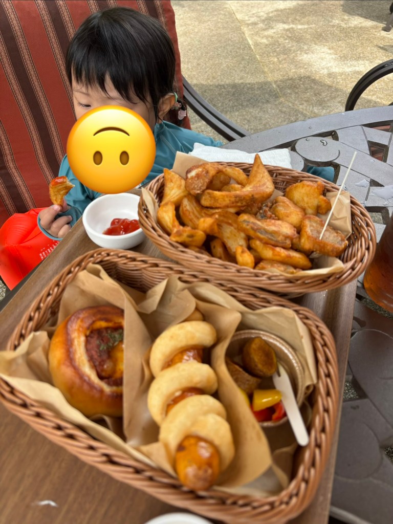 子供がポテトとウィンナーを食べている風景。テーブルにはポテトと料理が入ったバスケットが並び、ケチャップの入った小皿も見える。